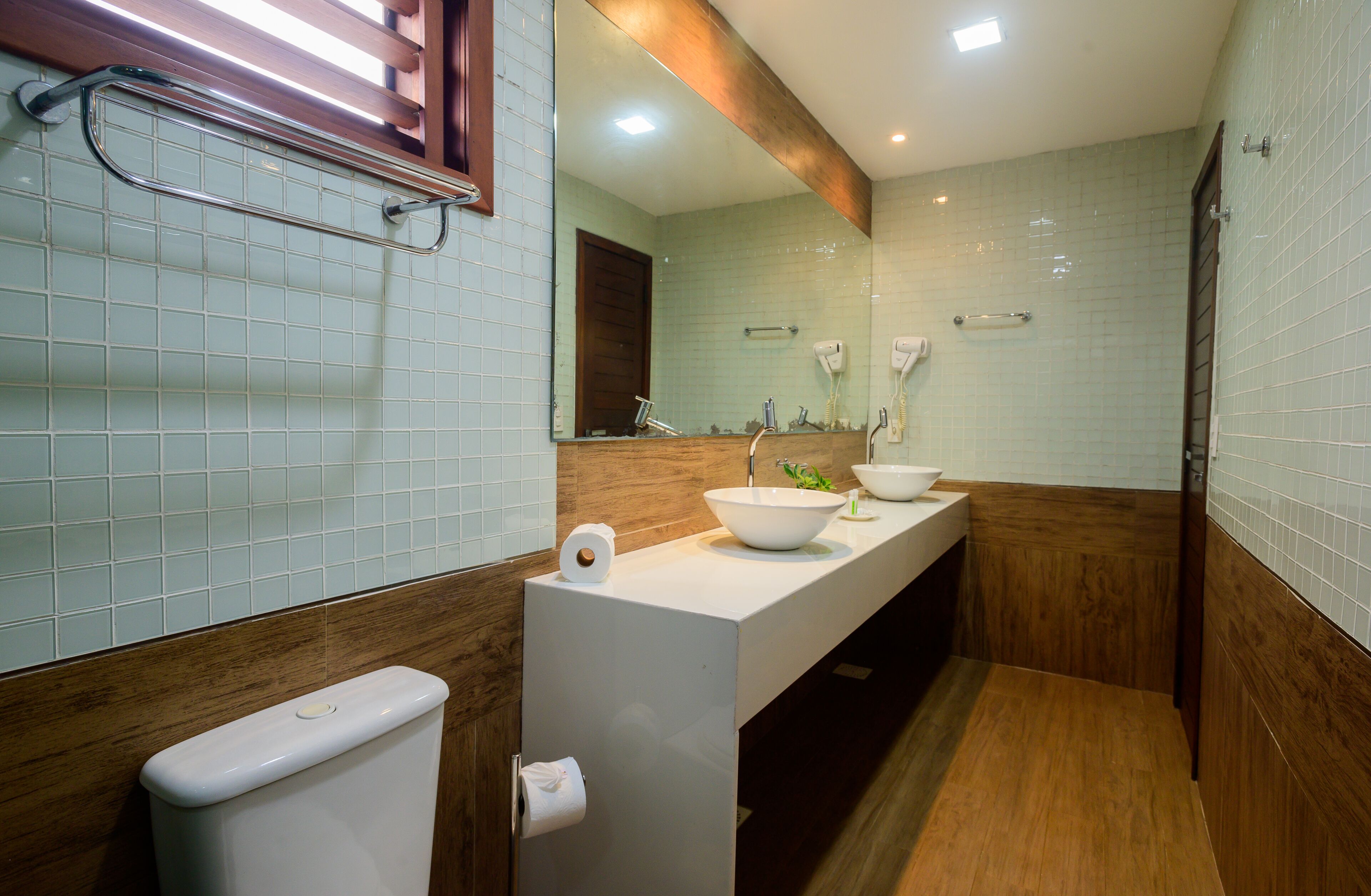 A modern bathroom with a white sink, a large mirror, and a wooden vanity.