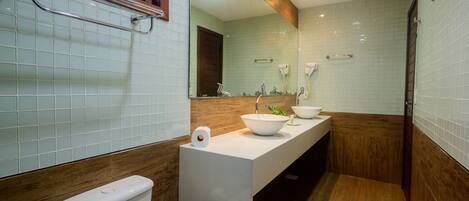 A modern bathroom with a white sink, a large mirror, and a wooden vanity.