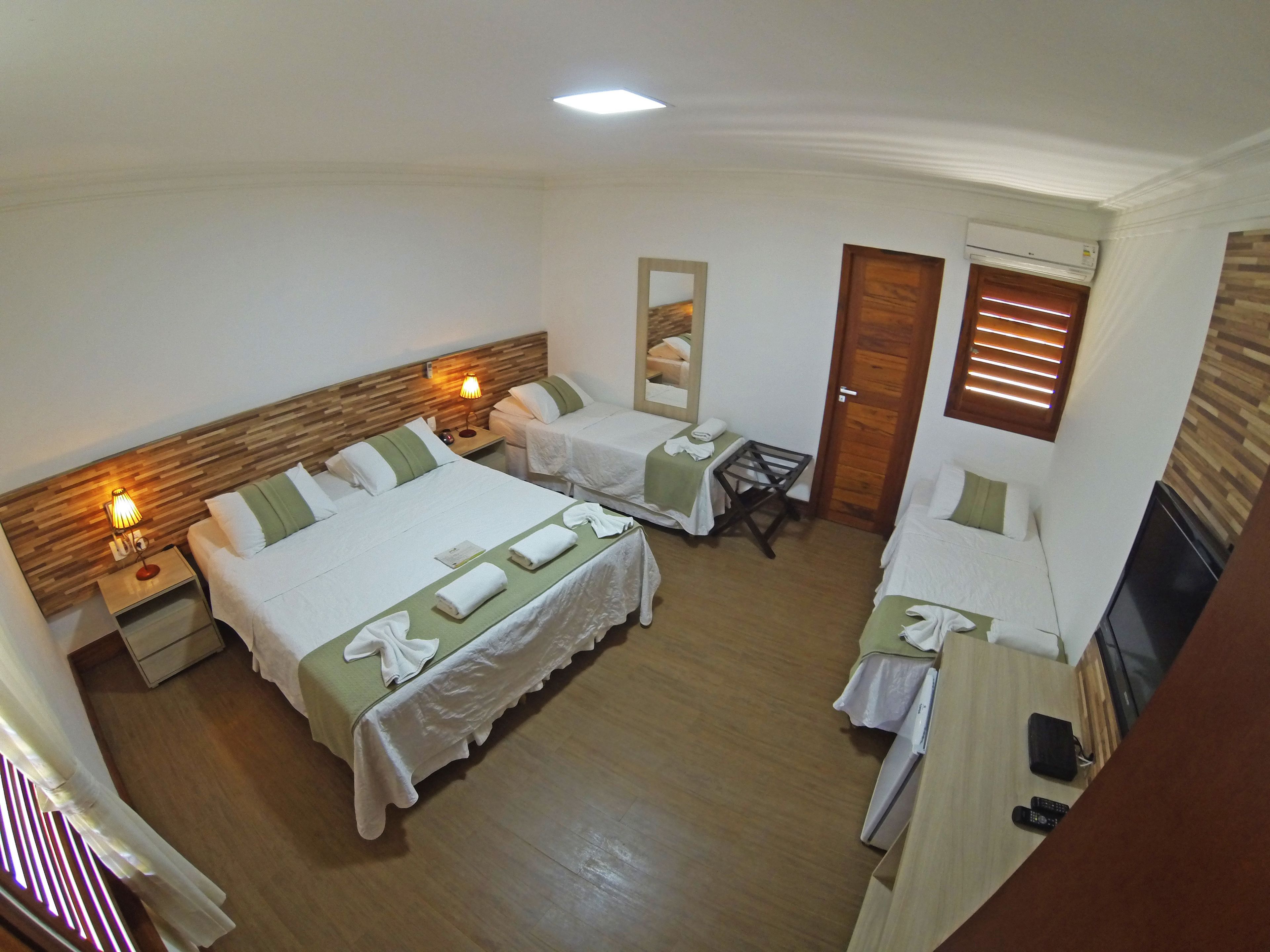 Une chambre d’hôtel avec deux lits, une petite table, un miroir et un appareil de climatisation.