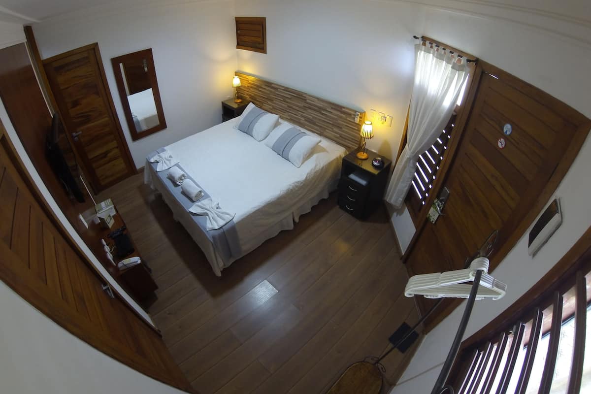 A bedroom with a bed, bedside tables, a lamp, a mirror, and a wooden door.