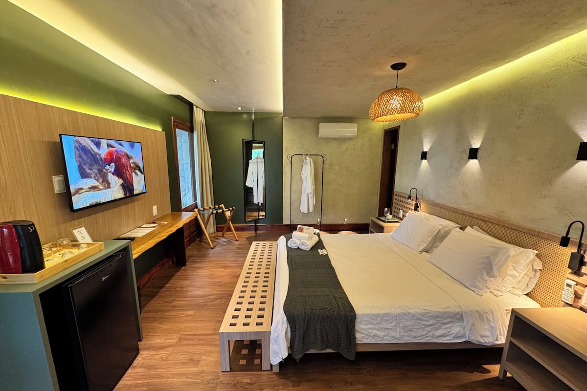 A hotel room with a bed, a TV, a desk, a mirror, and a wardrobe.