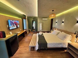 A hotel room with a bed, a TV, a desk, a mirror, and a wardrobe.