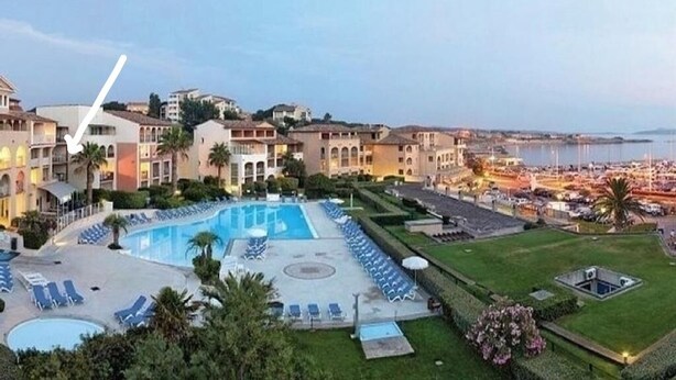 A resort with a large swimming pool, multiple lounge areas, and a view of the sea. - Beautiful T2 apartment in residence standing with pool facing the sea (Six-Fours-les-Plages)