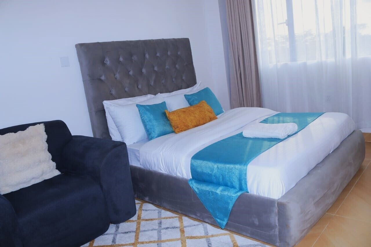 Een hotelkamer met een groot bed, een zwarte bank en een kamerkleed met dessin.
