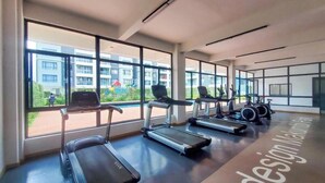 Ein modernes Fitnessstudio mit Laufbändern, Ergometer und einem großen Fenster mit Blick auf Wohnhäuser.