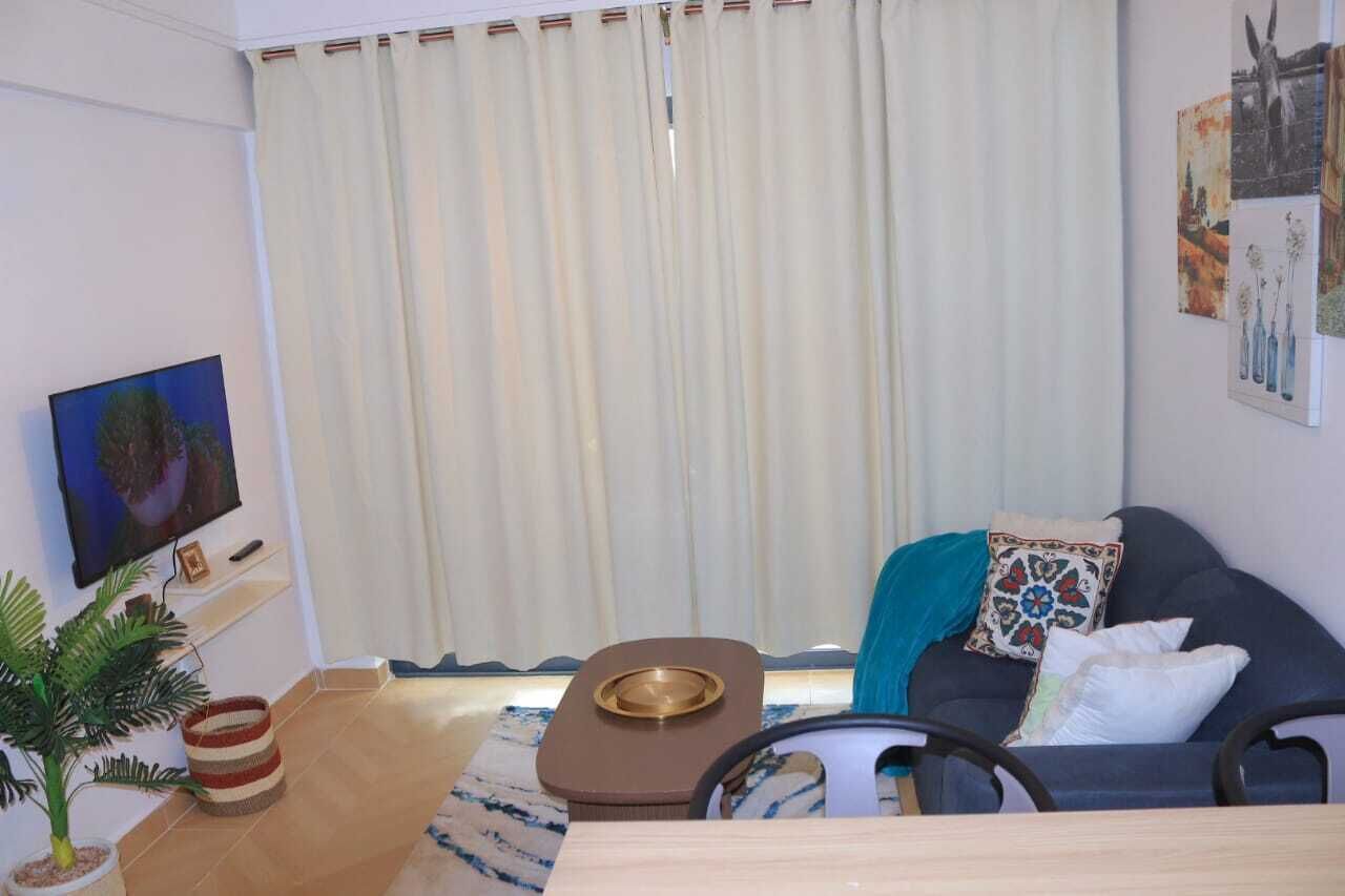 Ein Wohnzimmer mit einer Couch, einem Couchtisch, einem Fernseher und einer Topfpflanze.