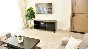 Ein modernes Wohnzimmer mit einem dunkelholznen Couchtisch, einem grauen Sofa, einer schwarzen Unterhaltungsanlage und einem großen abstrakten Gemälde an der Wand.