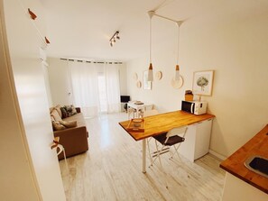 Une cuisine moderne dotée d’un plan de travail en bois, de meubles blancs et d’un coin repas avec une table et des chaises en bois.