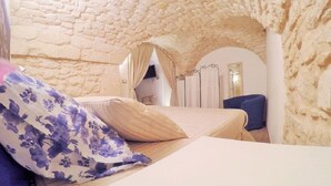 Ein Schlafzimmer mit Steindecke, einem Bett mit einem Blumenkissen und einem blauen Stuhl.