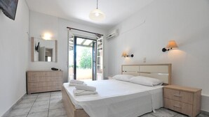 Una camera da letto con un letto, comodini, una cassettiera, uno specchio e una porta che dà su un balcone.