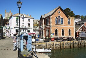 A historic building with arched windows and a clock, adjacent to a canal with a row of benches.