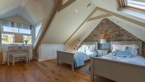 Un dormitorio con techo inclinado, cama, escritorio y ventana con vistas a un jardín.