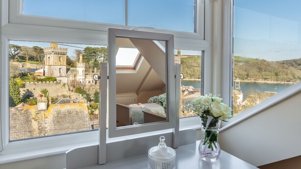 Una habitación con un amplio ventanal con vistas a un castillo histórico y un lago.
