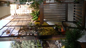A covered outdoor area with a metal gate, potted plants, and a wooden bench. - Large, elegant apartment on Janiculum hill, from 2 to 8 persons. (Roma)
