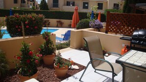 Un patio con piscina, mobiliario exterior y plantas en macetas.