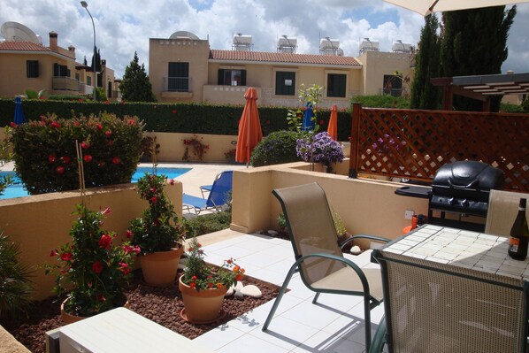 Eine Terrasse mit Pool, Sitzgelegenheiten und Grill.