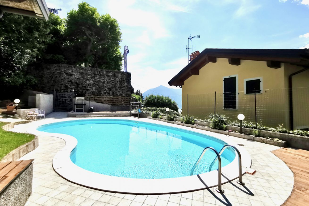 Une piscine avec un mur en pierre et un bâtiment doté d’un toit en pente.