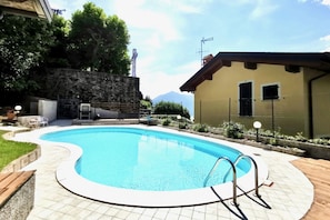A swimming pool with a stone wall and a building with a sloped roof.