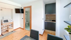 Ein kompakter Wohnbereich mit Küchenzeile, einem an der Wand montierten Fernseher und einer Holzeinrichtung mit Geräten.