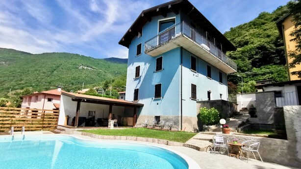Ein zweistöckiges Gebäude mit Balkon, Schwimmbecken und einer Terrasse mit Gartenmöbeln.