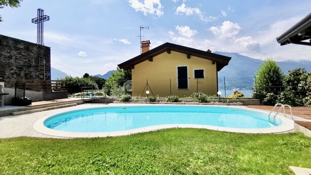 Une maison avec une piscine, un mur en pierre et des montagnes en arrière-plan.