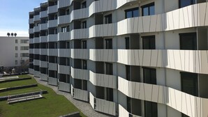 Un edificio moderno de varios pisos con balcones, techo plano y cielo despejado.