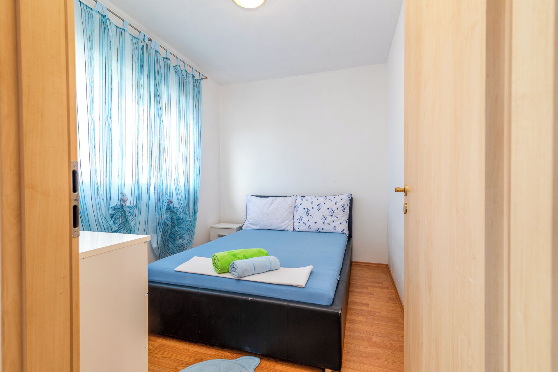 Une chambre à coucher avec un lit, une table de chevet et une fenêtre avec des rideaux.