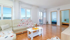 Ein geräumiges Wohnzimmer mit einer Couch, einem Couchtisch und Blick ins Freie.