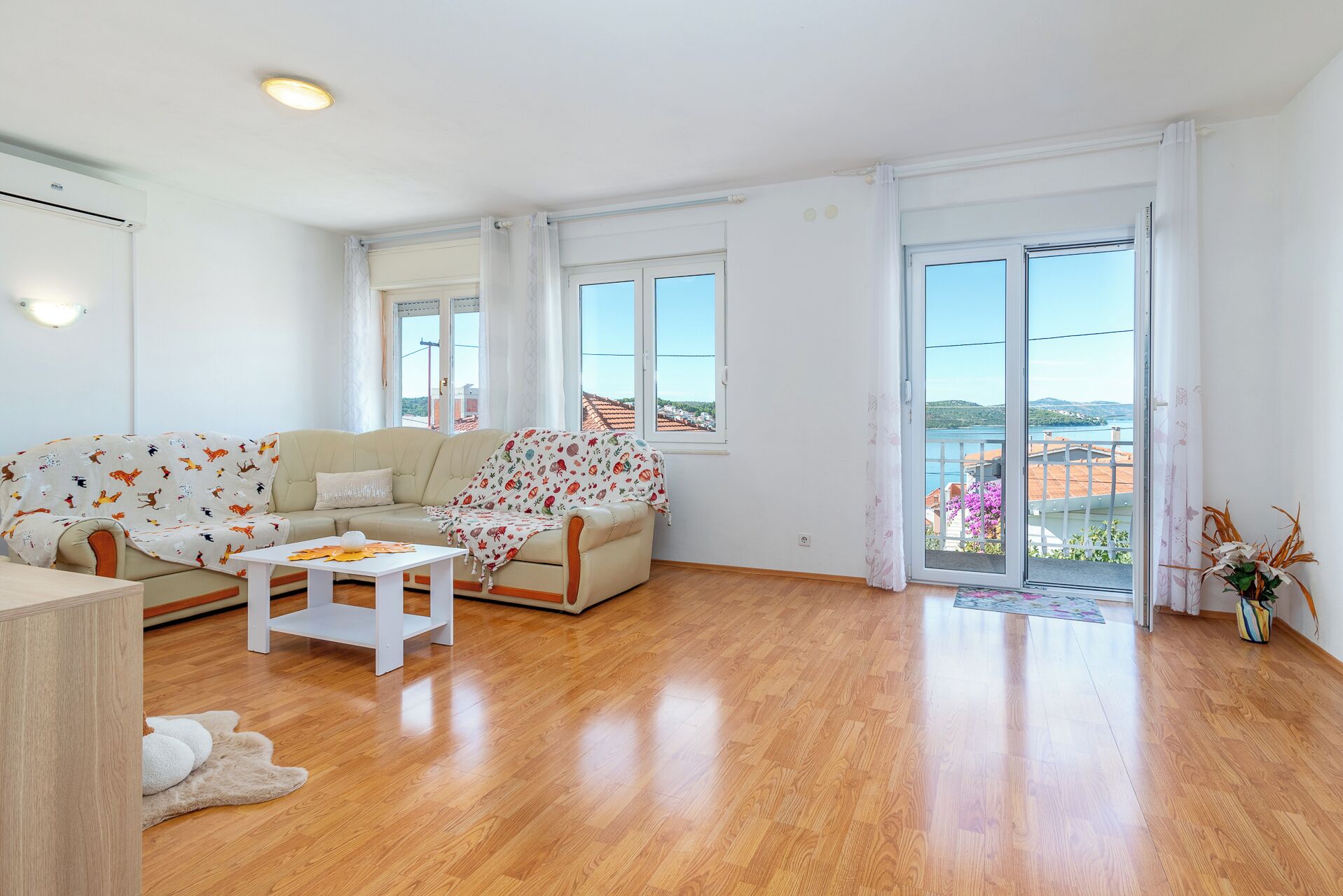 A spacious living room with a sofa, a coffee table, and a view of the sea through large windows.