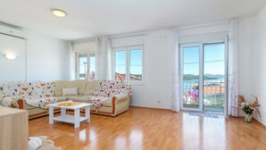 Ein großzügiges Wohnzimmer mit einer Couch, einem Couchtisch und Meerblick durch große Fenster.