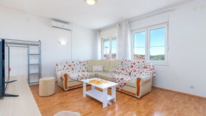 Ein helles Wohnzimmer mit einer Couch, einem Couchtisch und einer TV-Konsole.