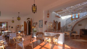 A spacious living area with wicker furniture, a staircase, and a fireplace. - Villa in dream location with private pool right by the sea (Siracusa)