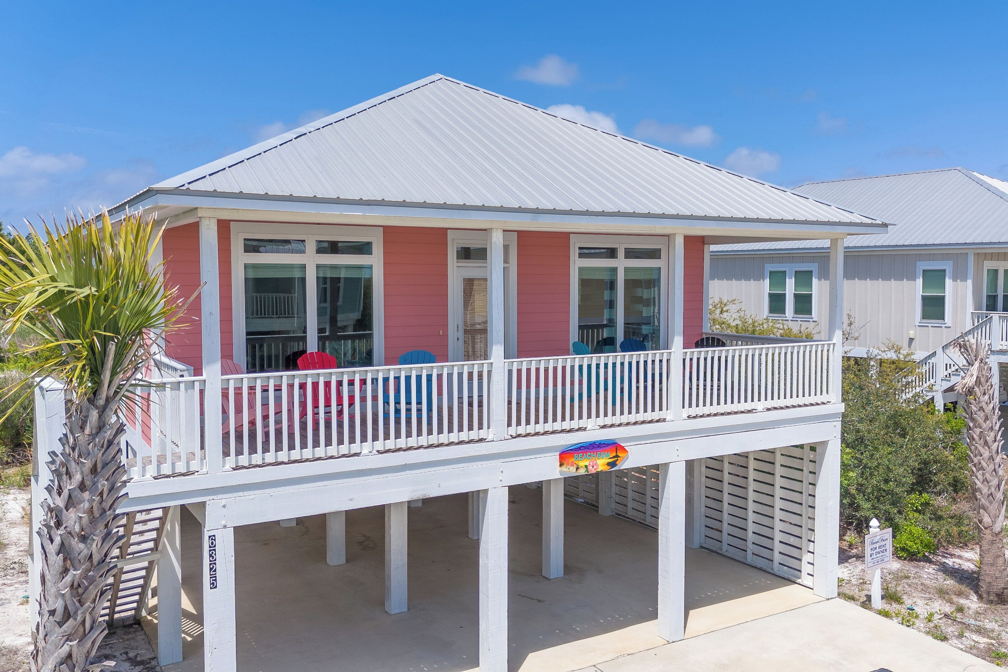 Una casa sulla spiaggia con un balcone, un ingresso coperto e un cartello che indica l'appartenenza a un beach club.