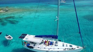 A sailboat named "ANTILLEAN" anchored in clear turquoise waters with a view of distant islands. - Come sail the Caribbean Sea aboard Antillean  (St thomas)