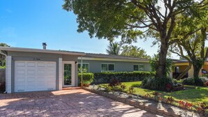 Una casa residenziale con garage, prato curato e un albero grande nel giardino antistante.