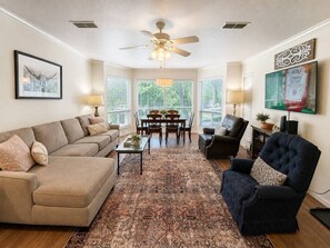 Ein Wohnzimmer mit Sofa, Sessel, Couchtisch und einem Essbereich mit Tisch und Stühlen.