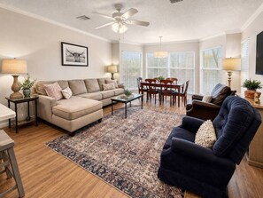 A living room with a sofa, armchair, dining table, and chairs.