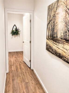 Ein Korridor mit Holzboden, einer weißen Tür und einer an der Wand befestigten Pflanze.