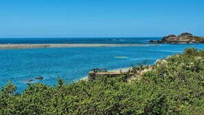 Eine Küstenlandschaft mit blauem Himmel, sandigem Strand und einem Felsen.