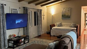 Un salón con un sofá, una mesa de centro, un televisor y un ventilador de techo.