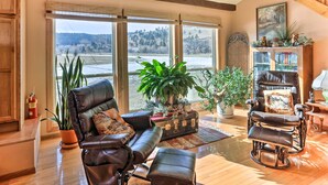 A cozy living room with a large window, leather chairs, a bookshelf, and a potted plant. - South Dakota Vacation Rental Near Mount Rushmore (Hermosa)