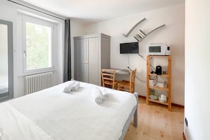 Ein Hotelzimmer mit Bett, Schreibtisch, Kleiderschrank, Fernseher und Mikrowelle.