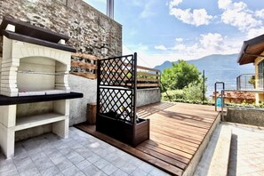 An outdoor kitchen area with a stone oven, a wooden deck, and a view of mountains.