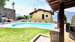 A house with a swimming pool, a stone wall, and a view of mountains. - BLUE HOUSE 1 by Design Studio (Bellano)