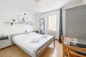 Een slaapkamer met een bed, nachtkastjes, een stoel, een tafel en een raam.