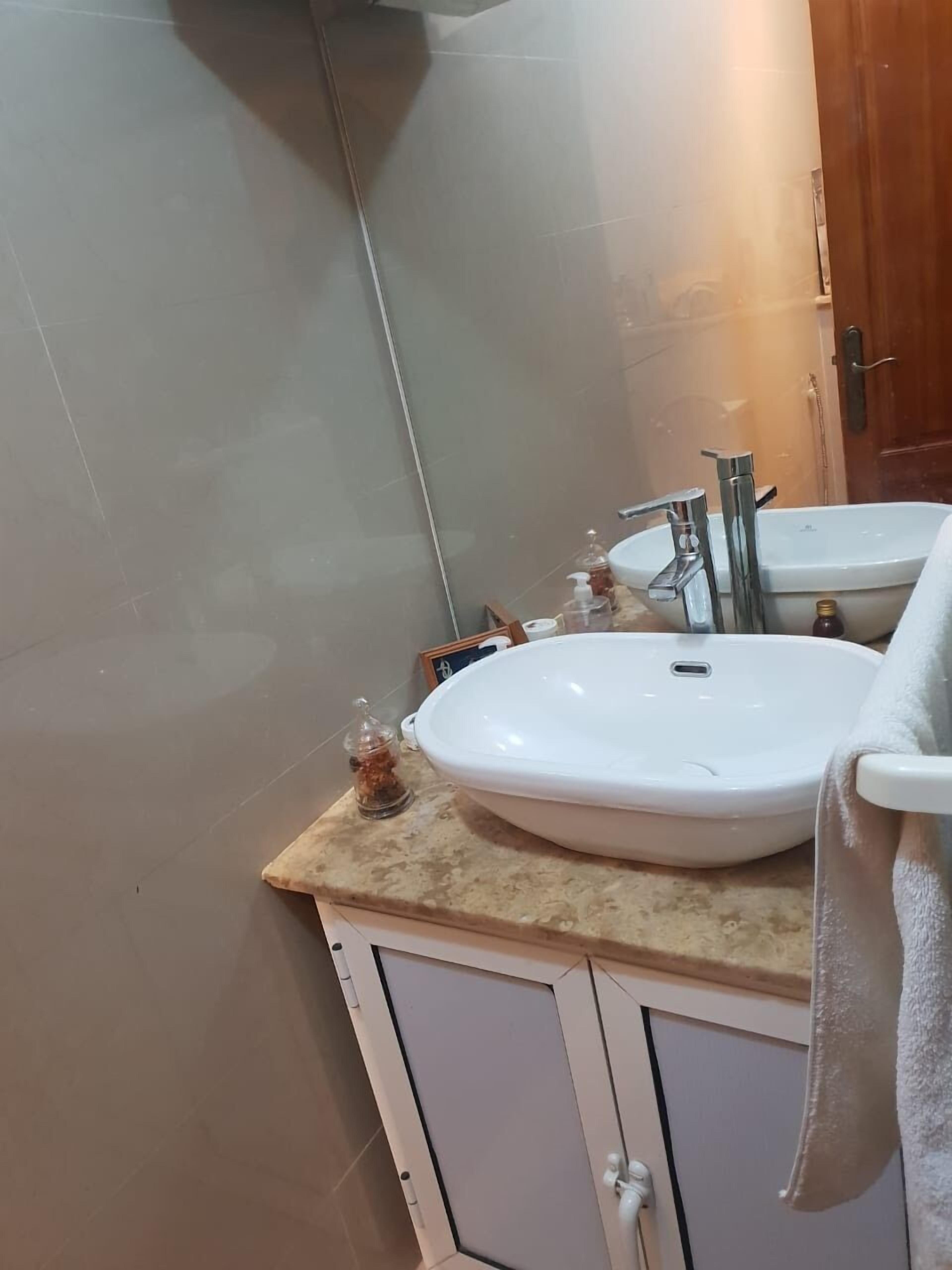 Une salle de bain avec un lavabo blanc, un miroir et une serviette accrochée au mur.