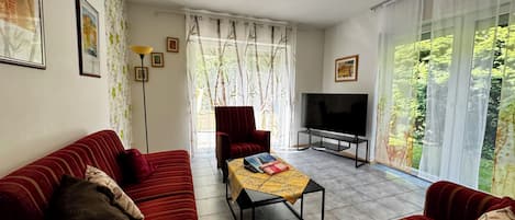 A living room with a sofa set, a TV, and a table with books.