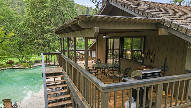 A wooden deck with outdoor furniture, a barbecue grill, and a swimming pool.
