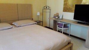A hotel room with a bed, a desk, a chair, a television, and a lamp. - B&B Villa il Glicine (Porto Mantovano)