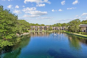 A hotel with a pool, surrounded by lush greenery and a clear blue sky.
